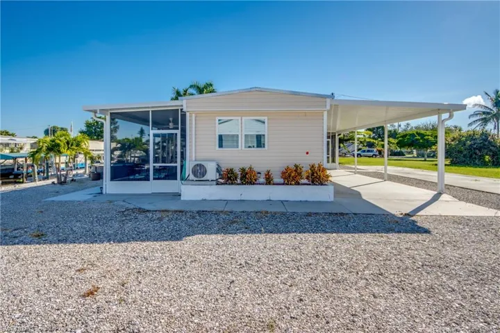 View of property exterior with an attached carport, a sunroom, and driveway