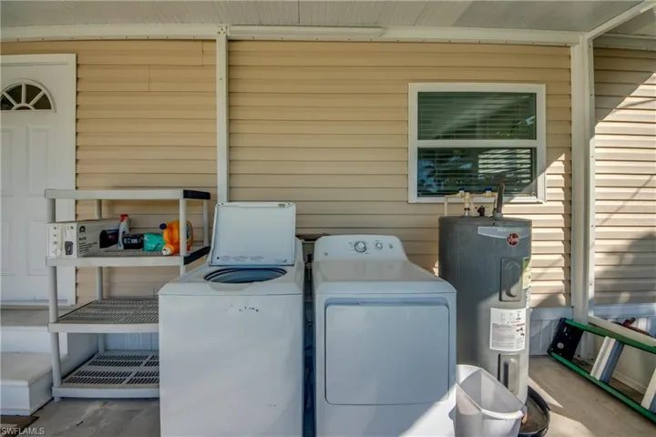 Laundry area featuring wood walls, water heater, and independent washer and dryer