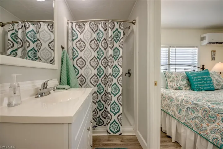 Bathroom with vanity, a shower stall, light wood-style floors, and a wall mounted AC