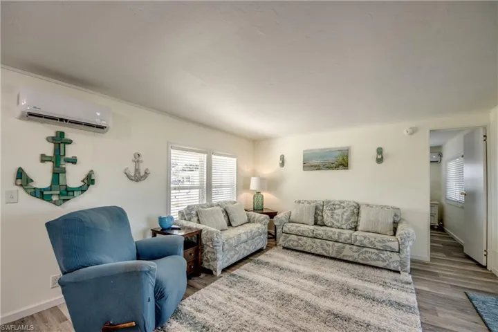 Living room with wood finished floors and a wall mounted AC