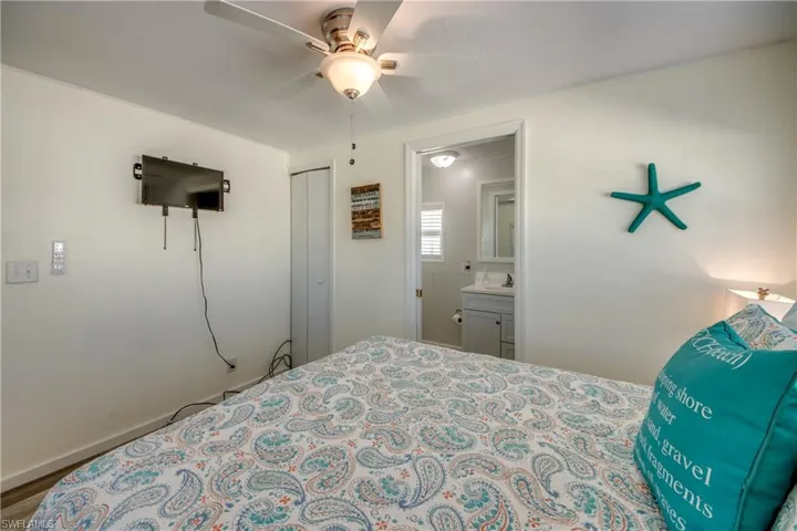 Bedroom with a ceiling fan, wood finished floors, a closet, and connected bathroom