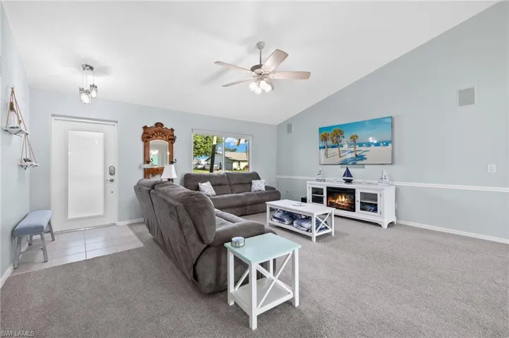 Living room featuring ceiling fan, light colored carpet, and lofted ceiling