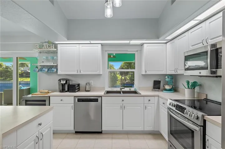 Kitchen featuring sink, white cabinets, light tile flooring, and stainless steel appliances