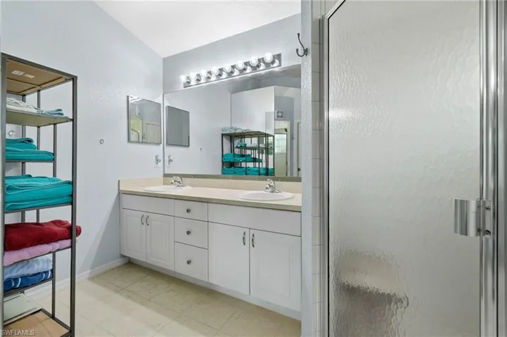 Bathroom with tile floors, an enclosed shower, and double sink vanity