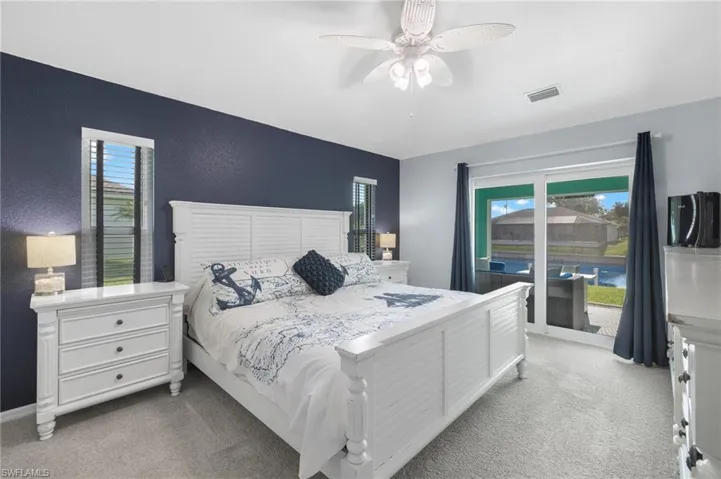 Bedroom featuring light carpet, ceiling fan, and multiple windows
