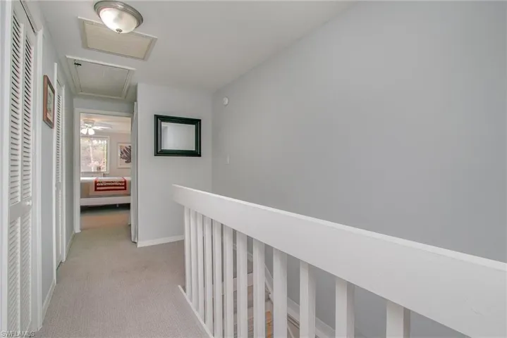 Corridor featuring light colored carpet