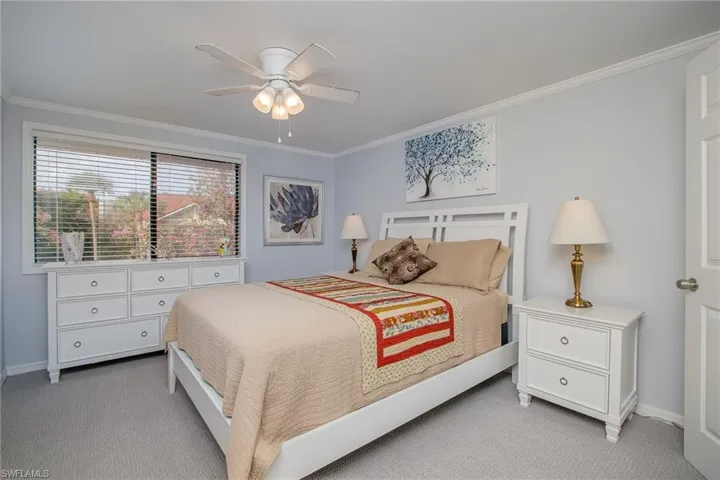 Carpeted bedroom featuring ceiling fan and ornamental molding