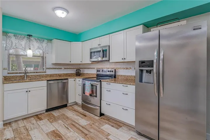 Kitchen featuring decorative light fixtures, white cabinetry, and stainless steel appliances