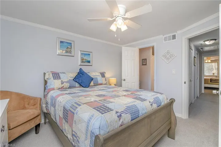 Bedroom with ceiling fan, light carpet, and ornamental molding