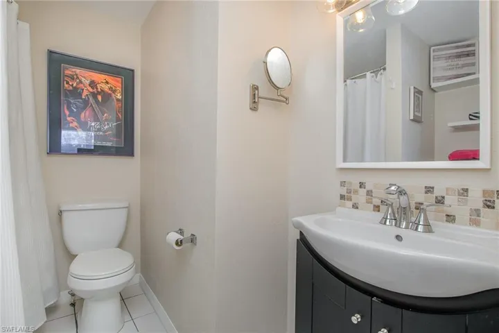 Bathroom with tile patterned flooring, vanity, tasteful backsplash, and toilet