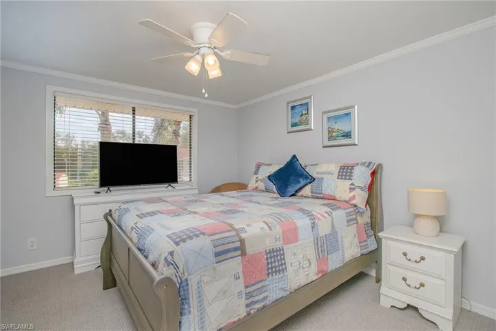 Carpeted bedroom with ceiling fan and ornamental molding