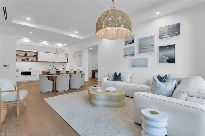 Living room with recessed lighting, light wood finished floors, crown molding, and a tray ceiling