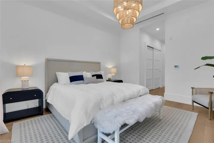 Bedroom featuring wood finished floors, a raised ceiling, baseboards, a closet, and a chandelier