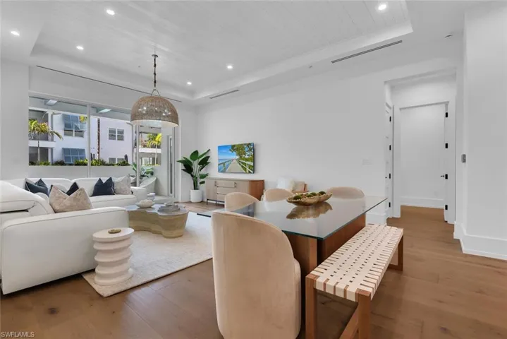 Dining room with a tray ceiling, wood finished floors, recessed lighting, wooden ceiling, and baseboards