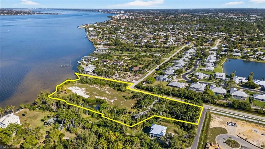 Aerial view of residential area featuring property boundaries highlighted and a nearby body of water