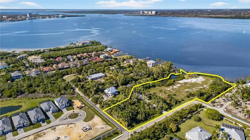Aerial view of residential area featuring a nearby body of water and property parcel outlined