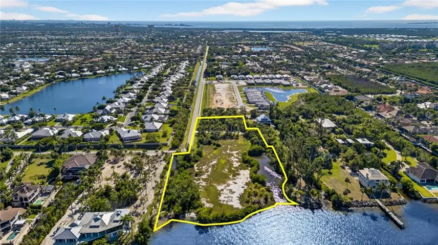 Aerial perspective of suburban area featuring property boundaries highlighted and a nearby body of water