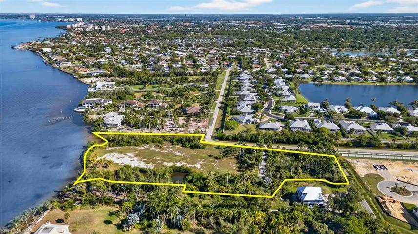 Aerial view of residential area with property boundaries highlighted and a large body of water