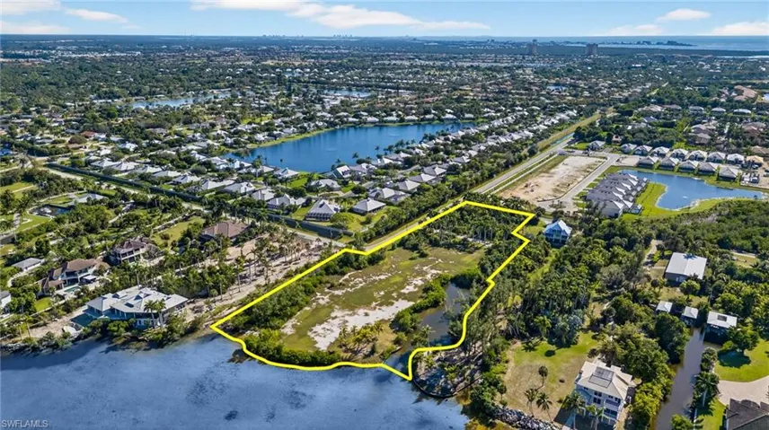 Aerial perspective of suburban area with property parcel outlined and a nearby body of water