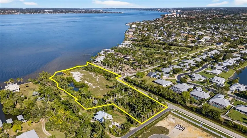 Aerial view of property and surrounding area featuring property parcel outlined and a large body of water