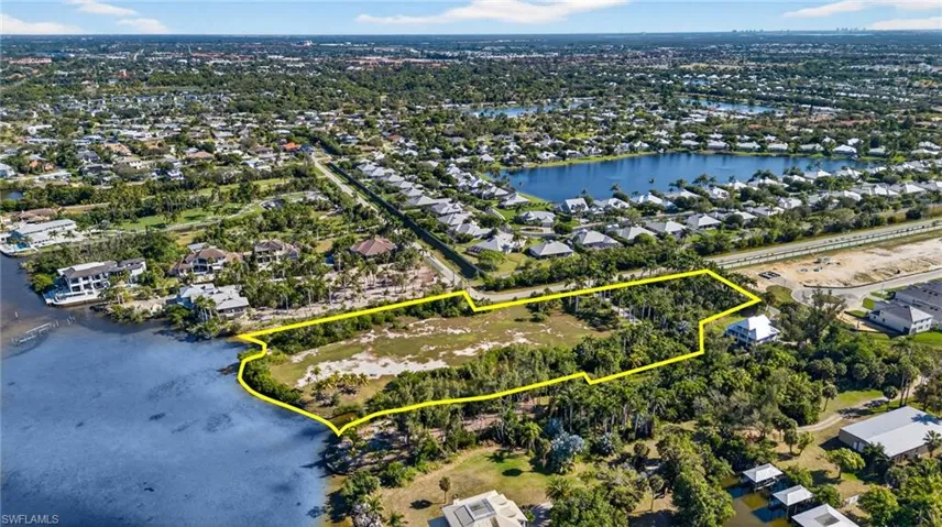 Aerial view of residential area featuring property boundaries highlighted and a large body of water