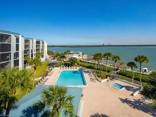 Expansive views of the water, a swimming pool, and a spa area with surrounding palm trees