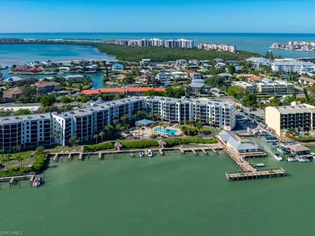 Waterfront property featuring a complex of multi-story buildings, a swimming pool, and a private boat dock with several boats