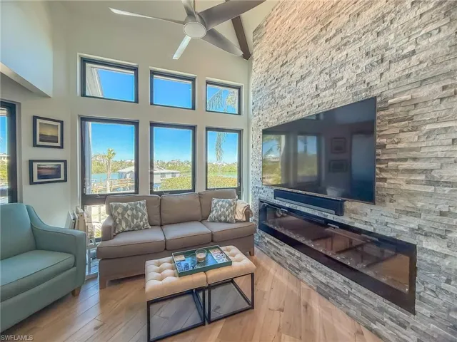 Living room featuring beamed ceiling, a high ceiling, ceiling fan, and hardwood / wood-style floors