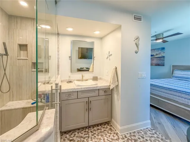 Bathroom featuring visible vents, a shower stall, baseboards, ceiling fan, and vanity