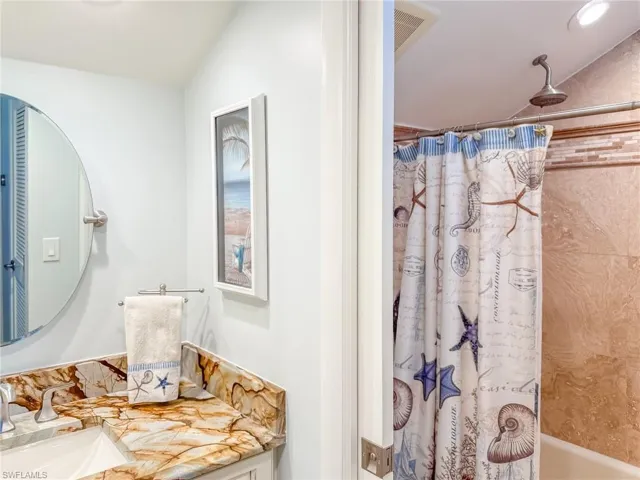 Bathroom featuring vanity, lofted ceiling, shower / bath combination with curtain, and visible vents
