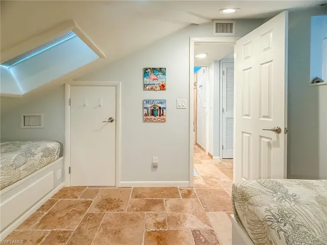 Bedroom featuring lofted ceiling, stone tile floors, and visible vents
