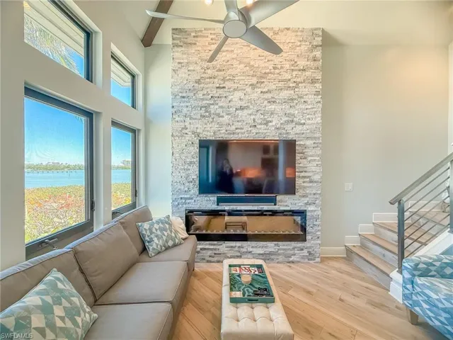 Living area with ceiling fan, beamed ceiling, stairway, a high ceiling, and wood finished floors
