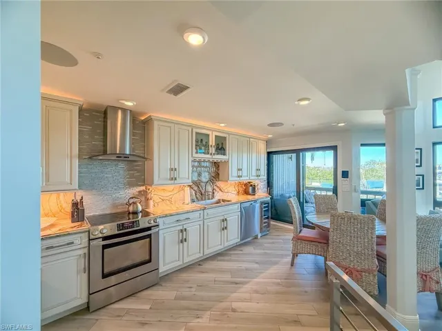 Kitchen with visible vents, a sink, tasteful backsplash, appliances with stainless steel finishes, and wall chimney range hood