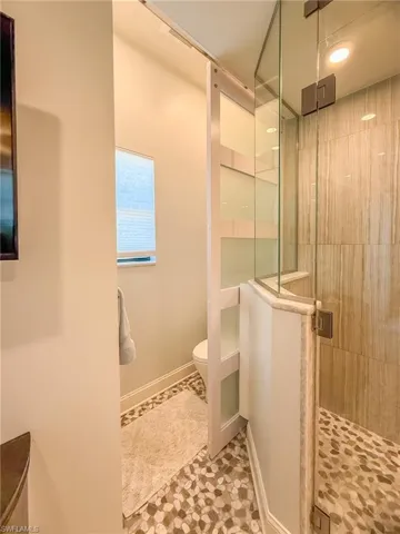 Full bathroom featuring a shower stall, toilet, and baseboards