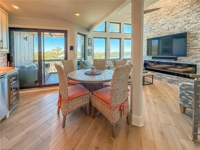 Dining space with beverage cooler, light wood-type flooring, a wealth of natural light, and high vaulted ceiling
