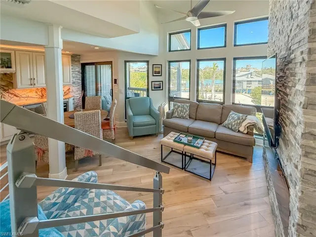 Living area featuring visible vents, a high ceiling, a ceiling fan, and light wood finished floors