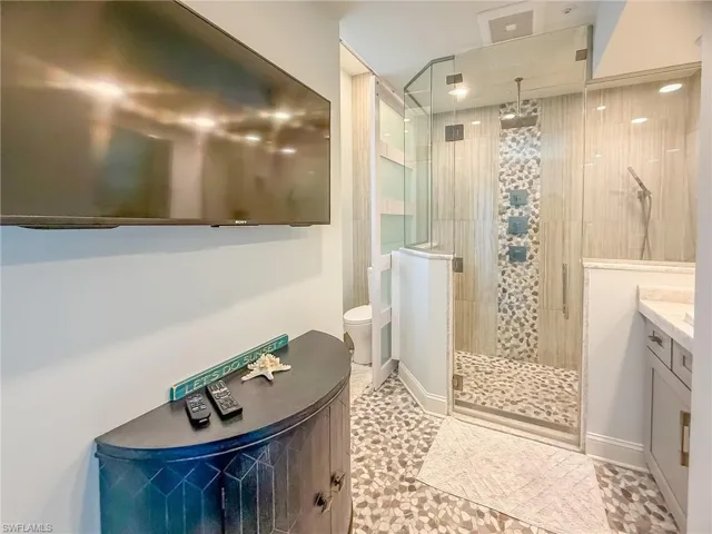 Bathroom with baseboards, toilet, a stall shower, and vanity