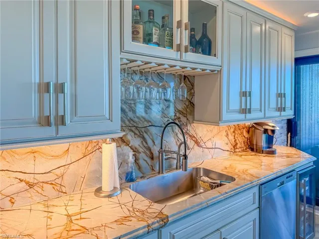 Kitchen with a sink, light countertops, glass insert cabinets, dishwasher, and tasteful backsplash