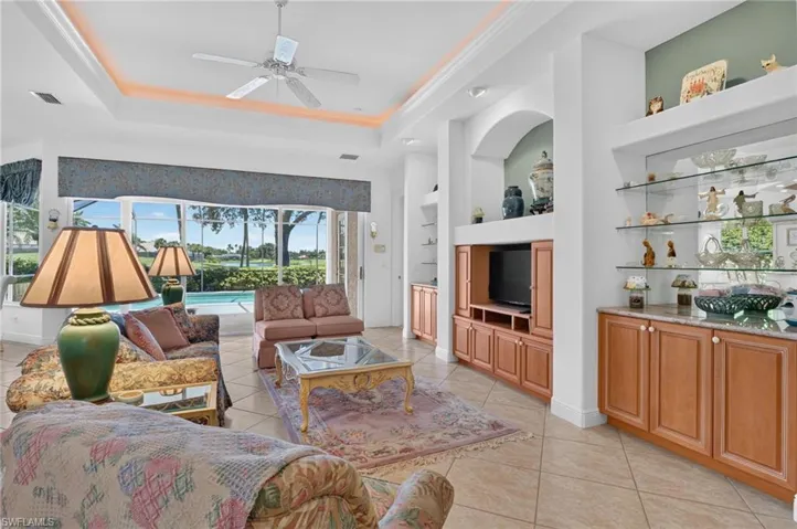 The living area features a lighted tray ceiling and built in shelves and cabinets.