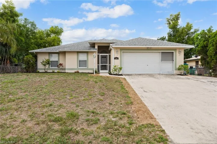 Ranch-style home with stucco siding, a garage, and driveway