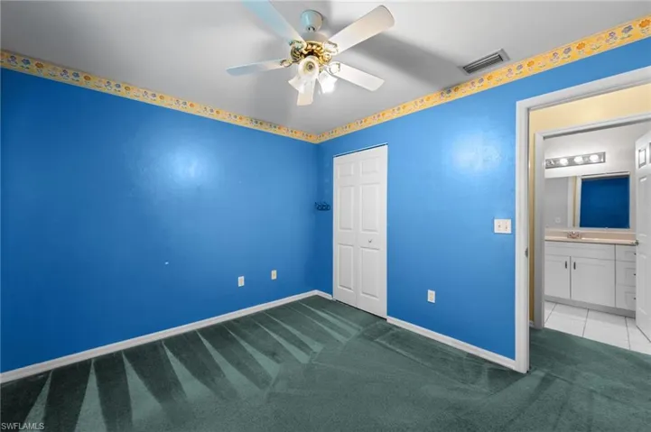 Unfurnished bedroom featuring carpet floors, baseboards, a closet, a sink, and a ceiling fan