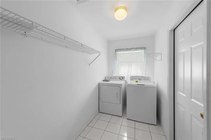 Laundry area featuring washer and dryer, baseboards, and light tile patterned flooring