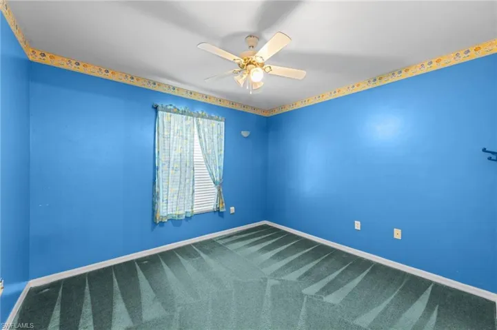 Carpeted empty room featuring a ceiling fan and baseboards
