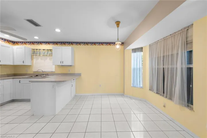 Kitchen featuring a peninsula, white cabinetry, a sink, baseboards, and recessed lighting