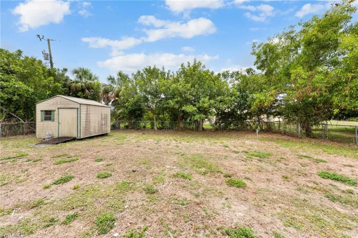 Fenced backyard with view of wooded area