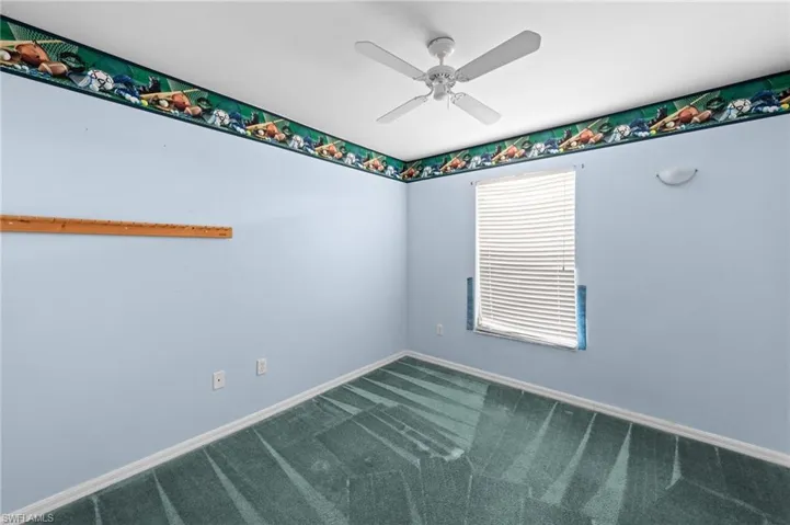 Empty room featuring carpet, a ceiling fan, and baseboards