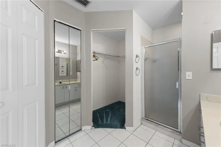 Full bath with vanity, a shower stall, and a walk in closet