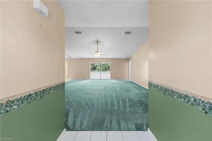Carpeted spare room featuring a ceiling fan and baseboards
