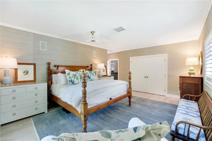Bedroom with a closet, light wood-style floors, a ceiling fan, and crown molding