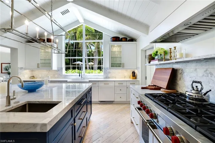 Kitchen featuring under cabinet range hood, premium stove, pendant lighting, glass insert cabinets, and white cabinets